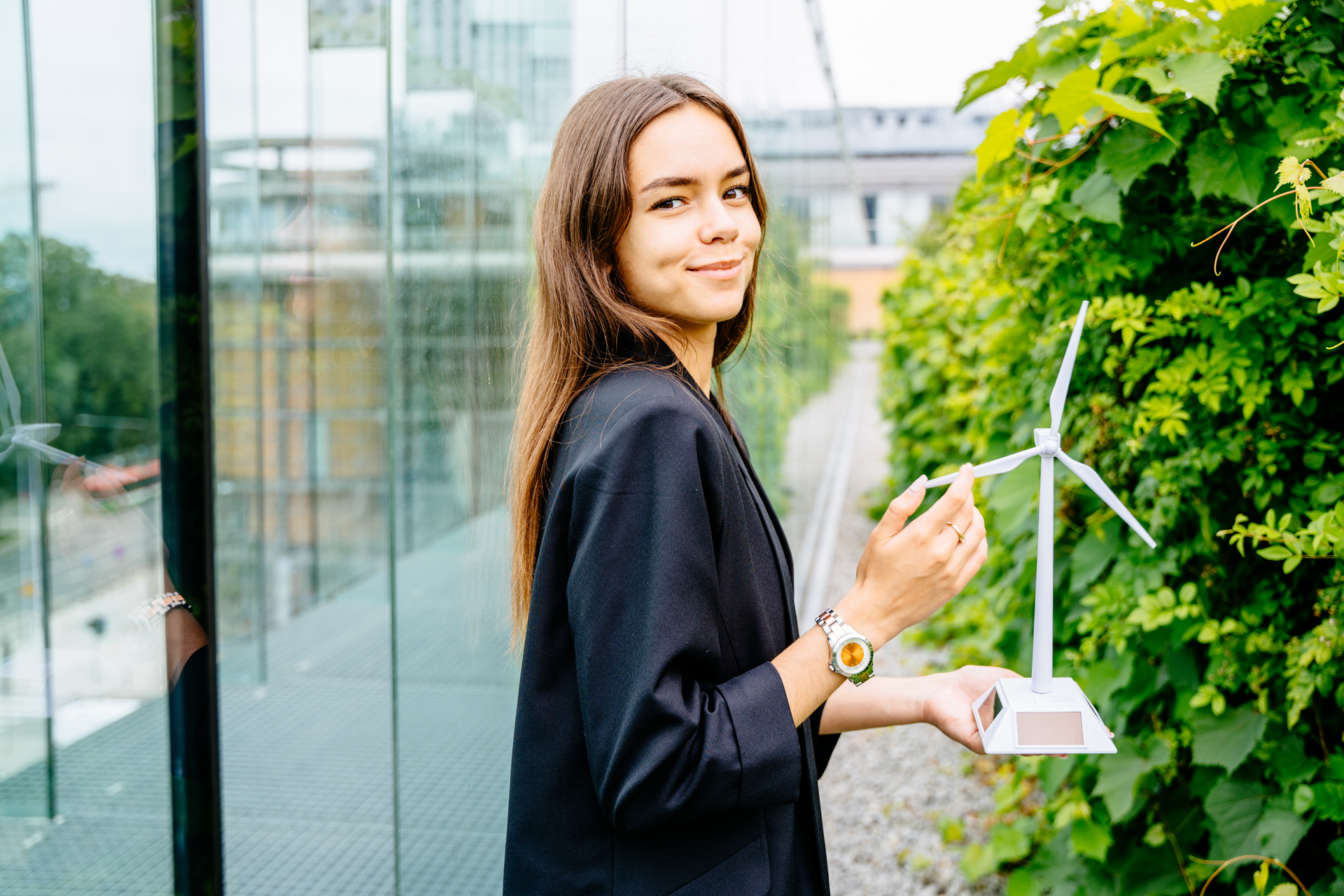 Young professional woman outside holding a small model of a wind turbine.