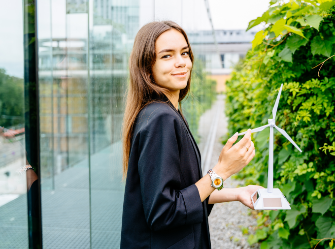 Young professional woman outside holding a small model of a wind turbine.